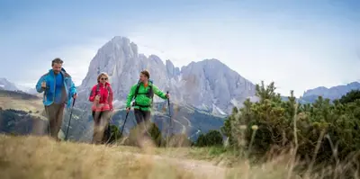 a group of three people walking on a mountain at Hotel Weisses Rössl - Cavallino Bianco in Ortisei