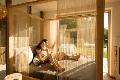 a couple sitting on a bed looking out the window at Hotel Weisses Rössl - Cavallino Bianco in Ortisei
