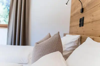 a bed with white pillows and a wooden headboard at Hotel Weisses Rössl - Cavallino Bianco in Ortisei
