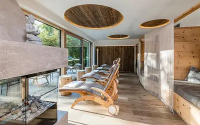 a row of chairs in a room with a fireplace at Hotel Weisses Rössl - Cavallino Bianco in Ortisei
