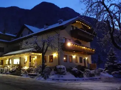 a house with christmas lights on it in the snow at Hotel Weisses Rössl - Cavallino Bianco in Ortisei