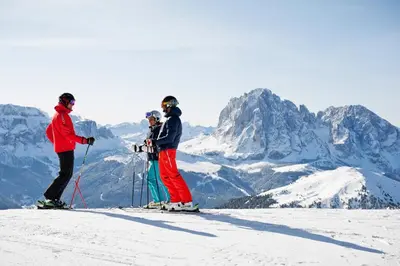 three people on skis on top of a mountain at Hotel Weisses Rössl - Cavallino Bianco in Ortisei