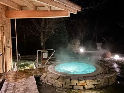 a hot tub in a garden at night at Hotel Weisses Rössl - Cavallino Bianco in Ortisei