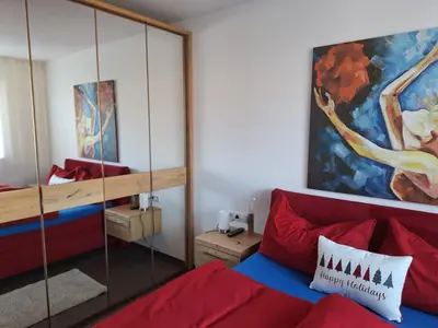 a living room with a red couch and a mirror at FeelHome Bruneck in Brunico