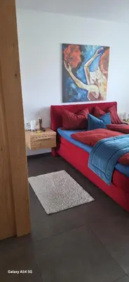 a bedroom with a red bed and a painting on the wall at FeelHome Bruneck in Brunico