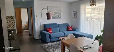 a living room with a blue couch and a table at FeelHome Bruneck in Brunico