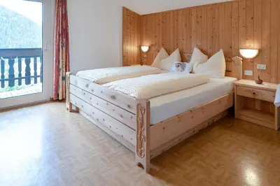 a bedroom with a large bed with a wooden wall at Apartments UDERA in Selva di Val Gardena