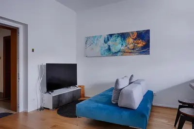 a living room with a blue couch and a flat screen tv at Duomo 55 MQ new flat in the centre of Bolzano in Bolzano