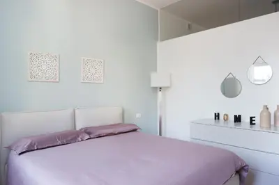a white bedroom with a bed with purple sheets at Duomo 55 MQ new flat in the centre of Bolzano in Bolzano