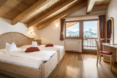 a bedroom with a bed and a table and chairs at B&B - Ciasa Rü Blanch in San Cassiano