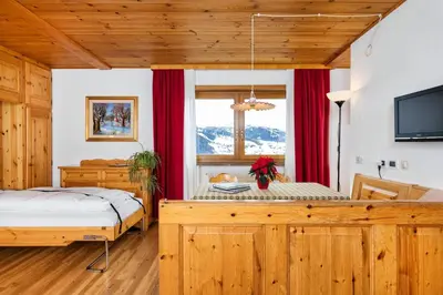 a bedroom with a bed and a window with red curtains at Apartments Antares in Colfosco