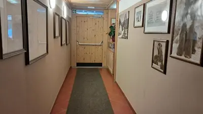 a hallway with a door and pictures on the walls at Apartments Antares in Colfosco