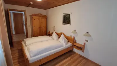 a bedroom with a bed with white sheets at Apartments Antares in Colfosco