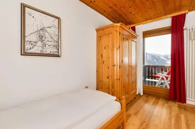 a bedroom with a bed and a large window at Apartments Antares in Colfosco