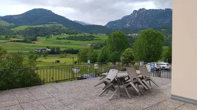 a table and chairs on a balcony with mountains at Appartamenti Bozzetta Marisa in Cavalese