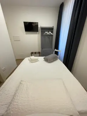 a bedroom with a white bed with a tv and a window at Al Palazzo in Cles
