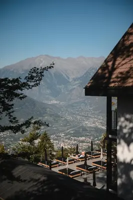a wooden table and chairs on a balcony with mountains at Miramonti Boutique Hotel in Avelengo