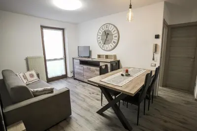a living room with a table and a clock on the wall at Mountain Hut Veronza in Cavalese