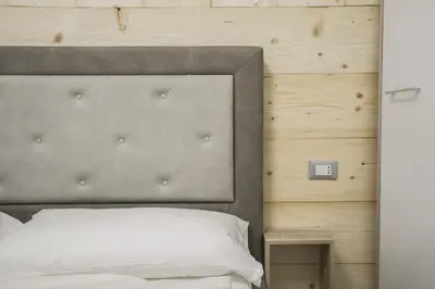 a bedroom with a bed with a gray headboard at Mountain Hut Veronza in Cavalese