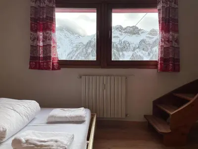 a bedroom with a bed and a window with snow covered mountains at Casa Eolo Falcade in Falcade