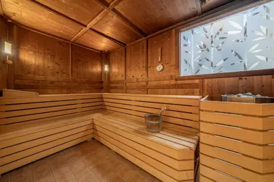 a wooden sauna with a window and a bucket in it at Hotel Adria in Merano