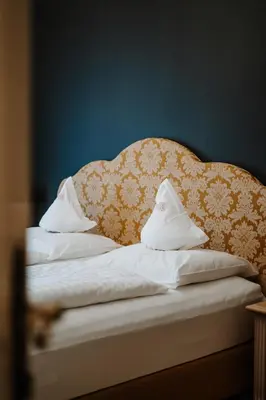 a bed with a headboard and white sheets and pillows at Hotel Adria in Merano