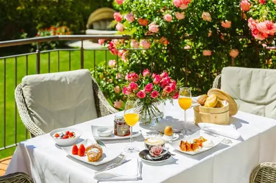a white table with food and glasses of orange juice at Hotel Pienzenau Am Schlosspark in Merano