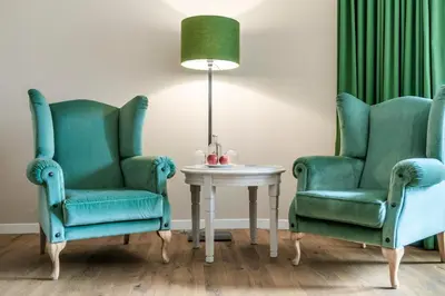 two green chairs and a table with a lamp at Hotel Pienzenau Am Schlosspark in Merano