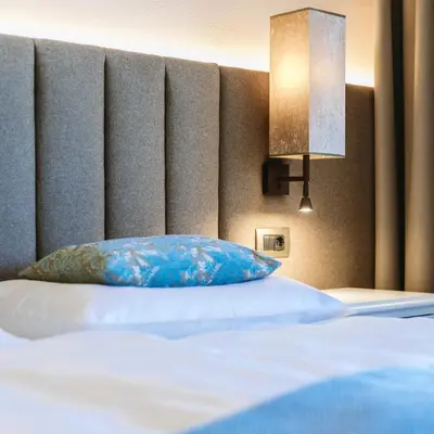 a bed with a blue pillow in a room at Hotel Pienzenau Am Schlosspark in Merano