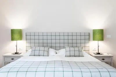 a bedroom with a blue and white bed with two lamps at Hotel Pienzenau Am Schlosspark in Merano
