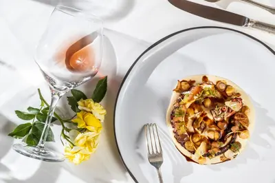 a plate with a pizza and a glass of wine at Hotel Pienzenau Am Schlosspark in Merano