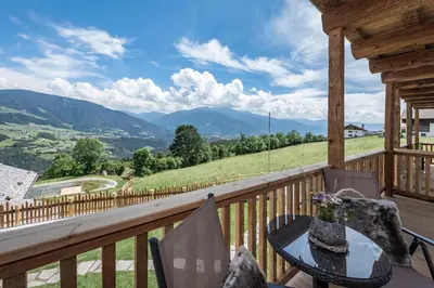 a log home with a large porch and a deck at DILIA Chalets & Apartments in Mühlbach