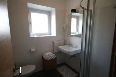 a bathroom with a sink and a toilet and a window at Residence Haus Ragen in Brunico