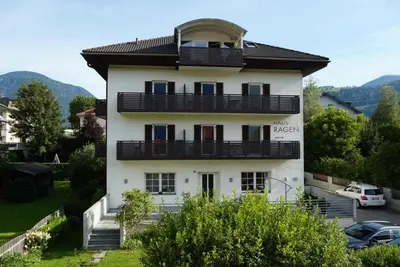 a white building with black balconies on top of it at Residence Haus Ragen in Brunico