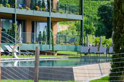 a swimming pool with chairs and a building at VILLA NAJ in Termeno
