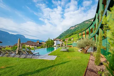 a resort with a pool and mountains in the background at VILLA NAJ in Termeno