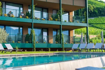 a hotel with a swimming pool in front of a building at VILLA NAJ in Termeno