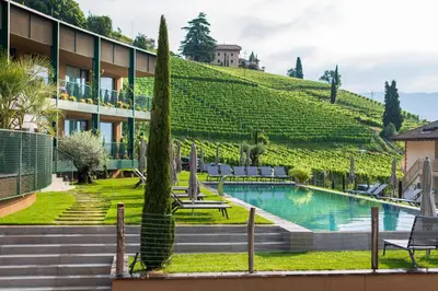 a hotel with a hill behind it with a swimming pool at VILLA NAJ in Termeno