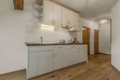 a kitchen with white cabinets and a wooden floor at Lüch da Fusse in Badia