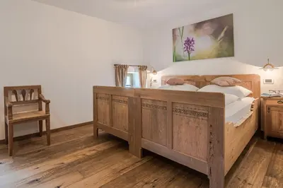 a bedroom with a wooden bed and a chair at Lüch da Fusse in Badia