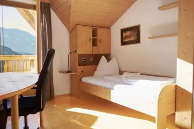 a bedroom with a bed and a desk and a table at Landhaus Anita Dolomiten Kronplatz in Perca