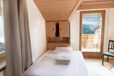 a bedroom with a bed and a large window at Landhaus Anita Dolomiten Kronplatz in Perca