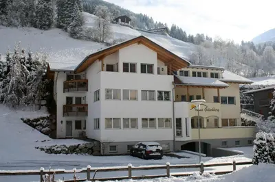 a building in the snow with a car parked in front at Gitschberg - Appartements in Vandoies