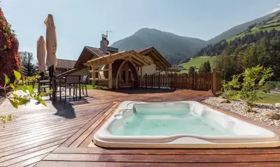 a hot tub on a deck with a house at Gitschberg - Appartements in Vandoies