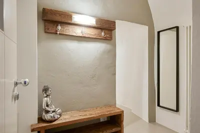 a statue sitting on a wooden bench next to a door at KARINA Lauben Lodge in Egna