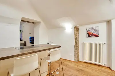 a kitchen with white walls and a counter and chairs at KARINA Lauben Lodge in Egna