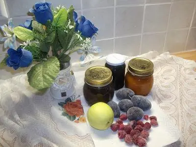two jars of jam and berries on a table with flowers at Waldoase in Schenna