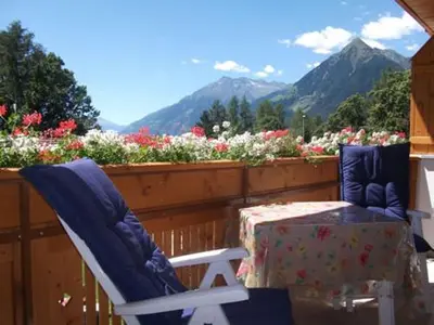 two chairs and a table on a balcony with flowers at Waldoase in Schenna
