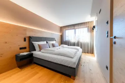 a bedroom with a large bed with a wooden wall at Rienz Alpine City Lofts in Brunico