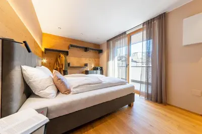 a bedroom with a large bed and a large window at Rienz Alpine City Lofts in Brunico